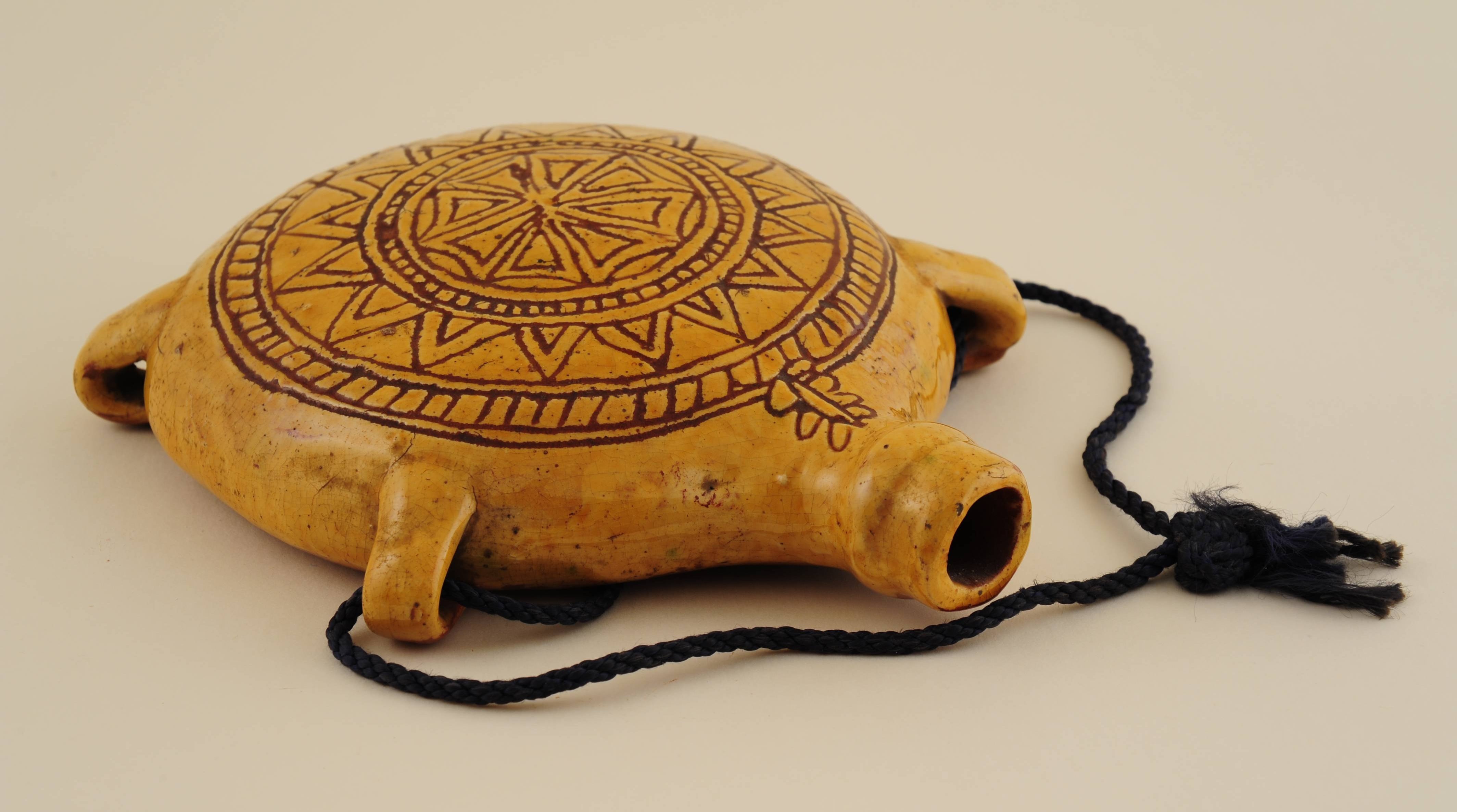 Decorative ceramic bottle with intricate designs on a beige background