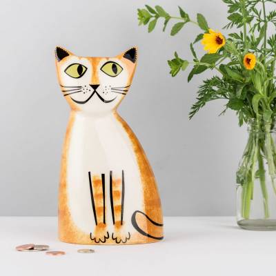 Ginger cat money box sat on table with coins