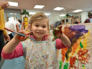 Child with painting brush at Burton Arts Lab
