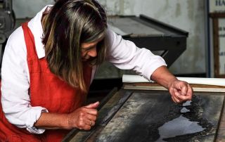 Photograph of artist maker Merlyn Chesterman demonstrating her printmaking craft