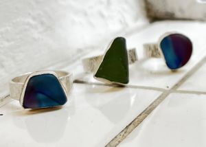 Image shows three silver sea glass rings resting on a white tiled surface