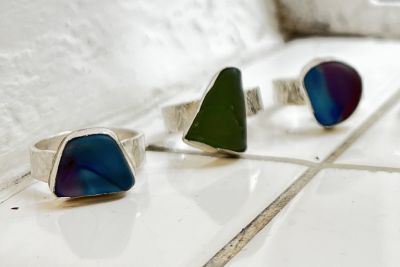 Image shows three silver sea glass rings resting on a white tiled surface