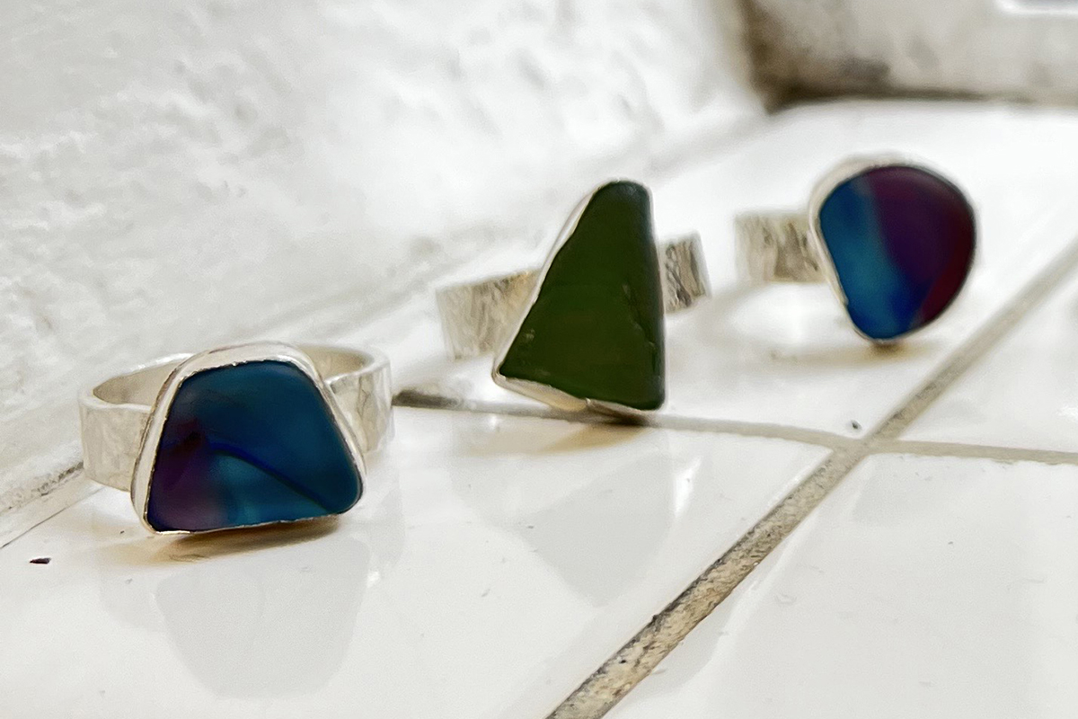 Image shows three silver sea glass rings resting on a white tiled surface