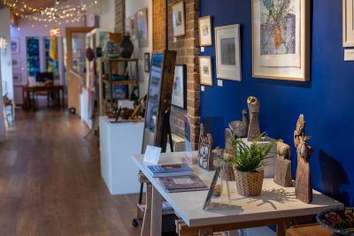 Image shows craft gallery at The Burton, tables with ceramics and art on the walls