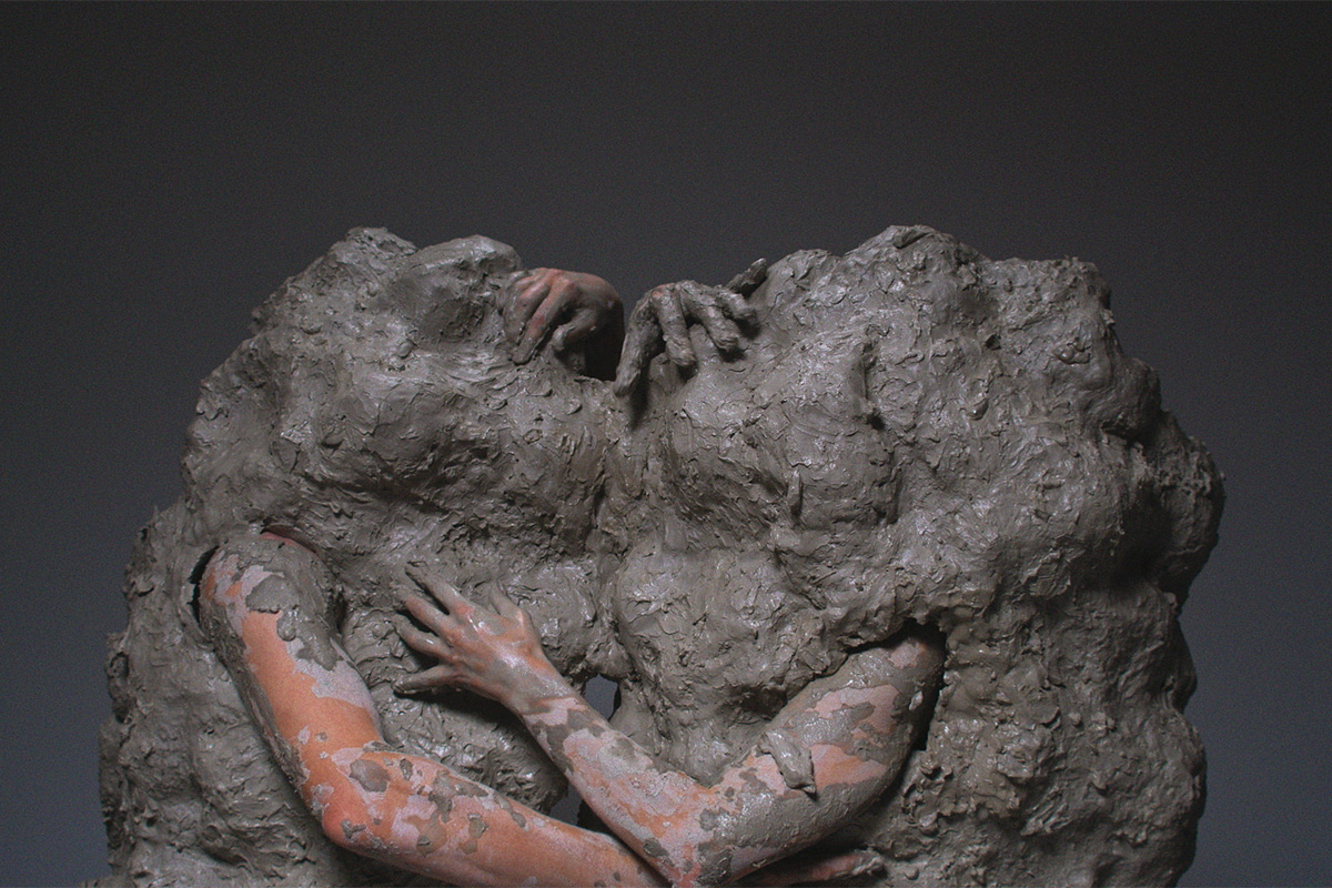 Image shows two people covered in clay