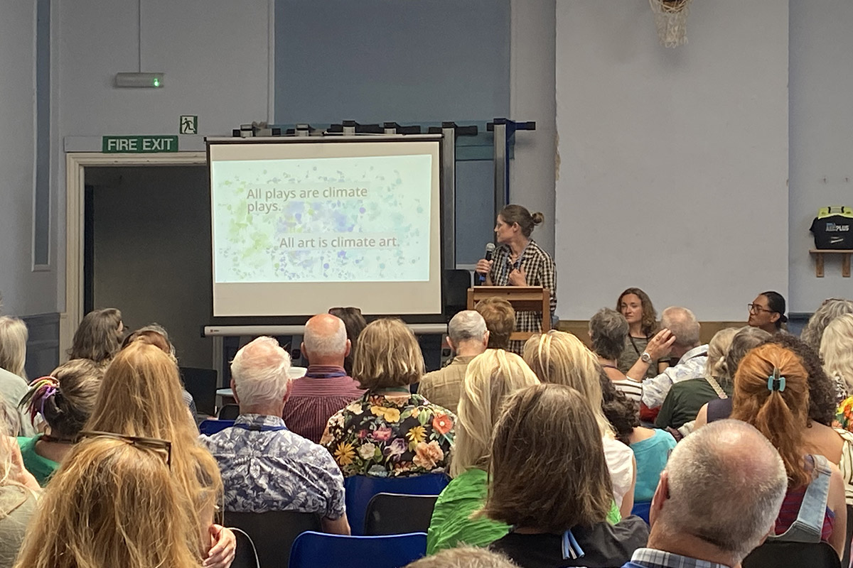 Image shows woman giving a talk in front of an audience