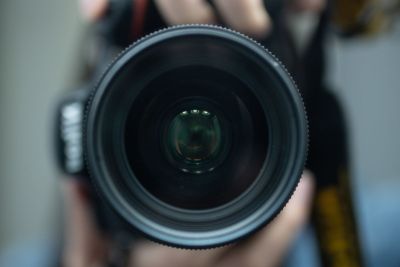 Image shows photographer holding camera lens