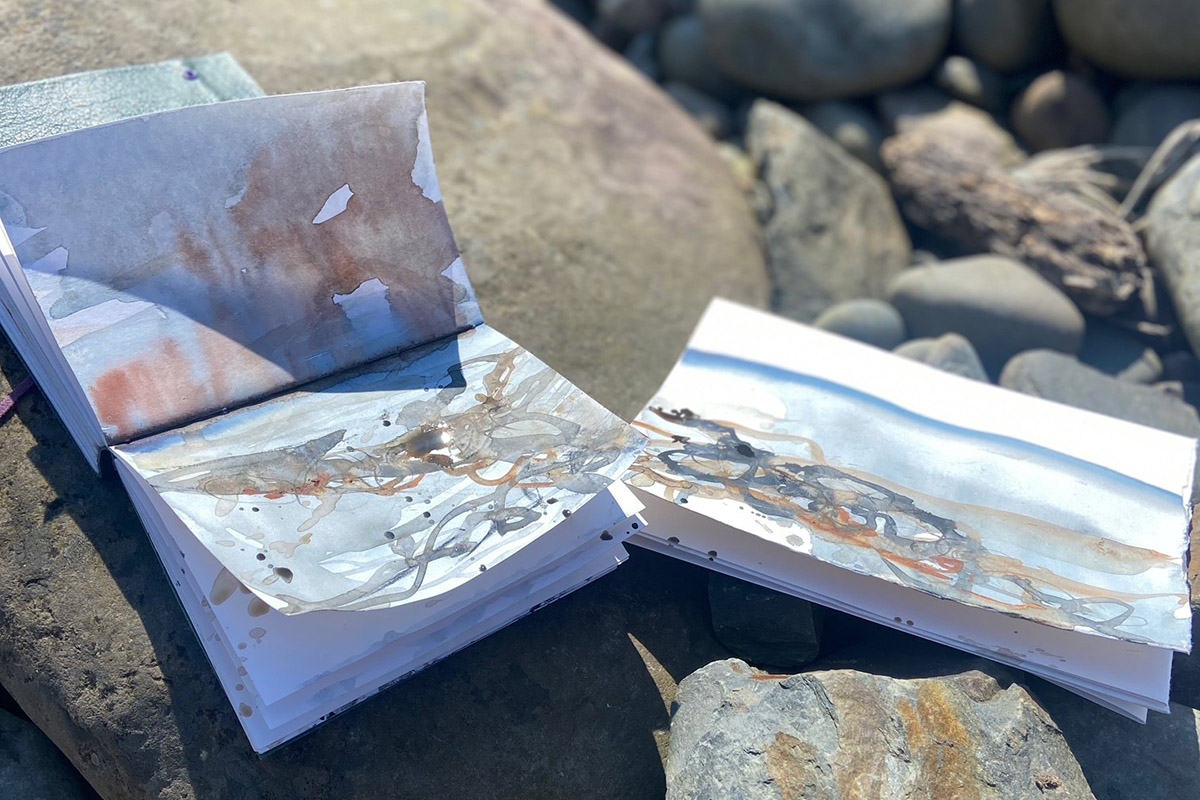 Artist sketchbooks on rocks during an en plein air watercolour workshop