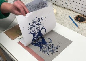 Image shows a lincocut print of a vase and flowers being revealed