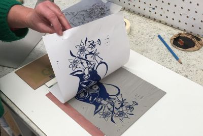 Image shows a lincocut print of a vase and flowers being revealed