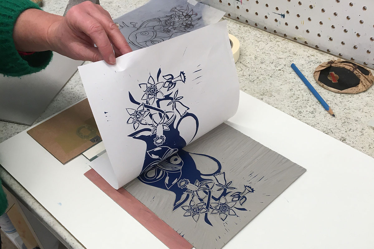Image shows a lincocut print of a vase and flowers being revealed