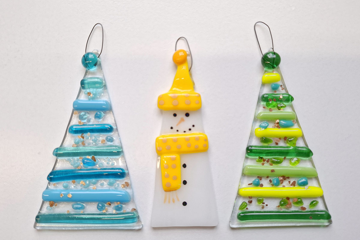 Image shows fused glass christmas decorations in the shape of a christmas trees and snowman