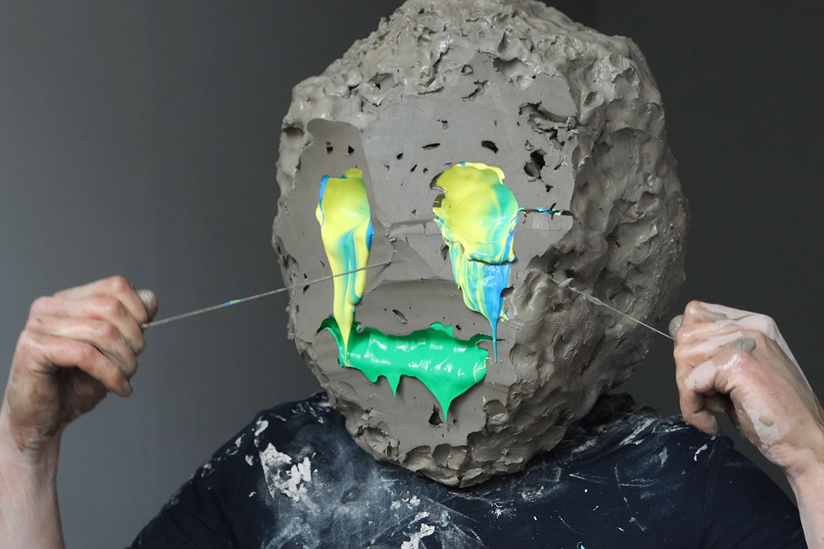 Will.je.suis (2020) by William Cobbing, showing a man with a clay head and yellow/green eyes and mouth