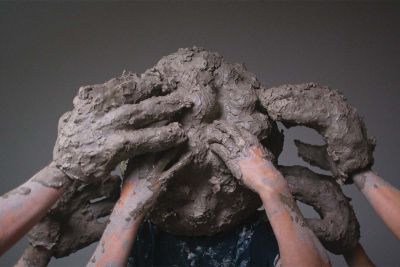 Image shows hands rubbing clay on a person's head, Mess of help (2023) by William Cobbing